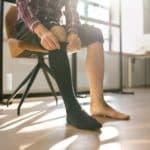 Man Putting On Medical Compression Stockings On Legs