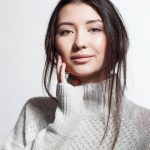 A woman in a sweater showing the results of laser treatments