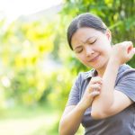 A woman scratching her arm due to an allergy flare-up, triggering an eczema flare-up and causing skin irritation