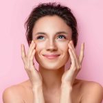 Woman with flawless skin on pink background representing beauty treatments like injectables and laser resurfacing