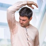 Man looks at his wet shirt after a long day of sweating.