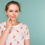 Teenage girl is not pleased with the acne on her face.